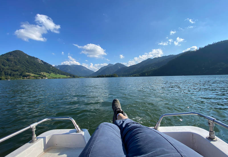 Bergpanorame vom Tretboot fotografiert mit Beinen im Vordergrund