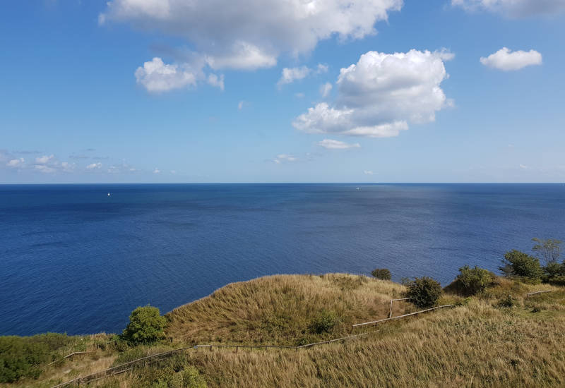 Blick übers Meer mit Dünengras und Hügel im Vordergrund