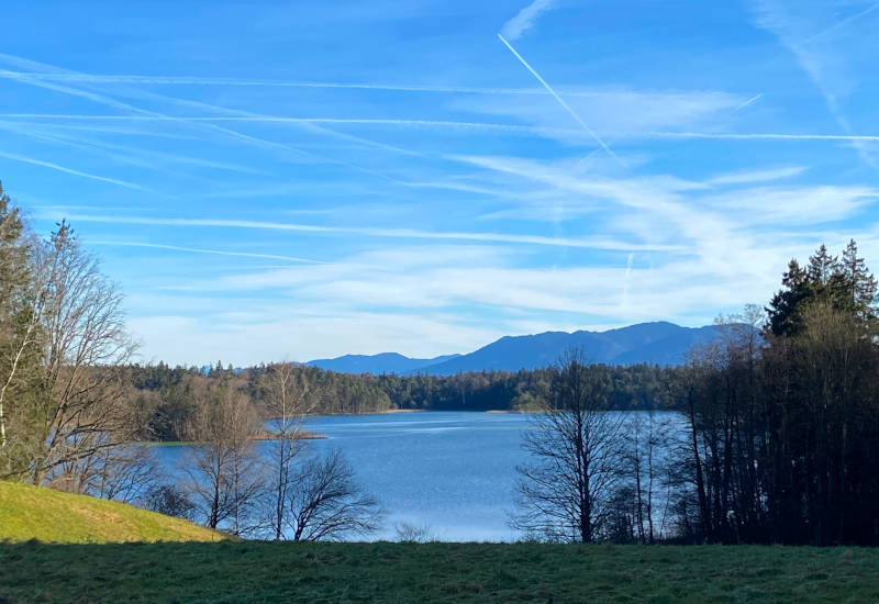Blick über den See in Richtung Berge mit blauem Himmel