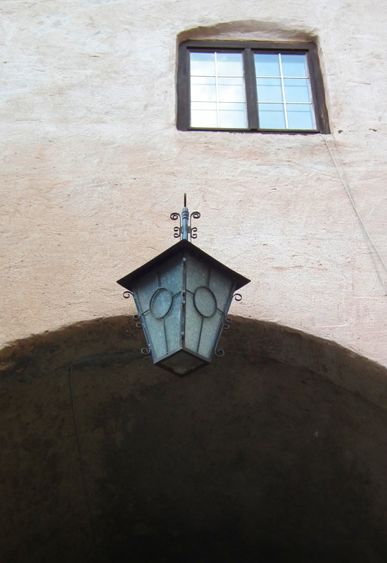 Laterne unter einem Bogen, Fenster im Hintergrund.