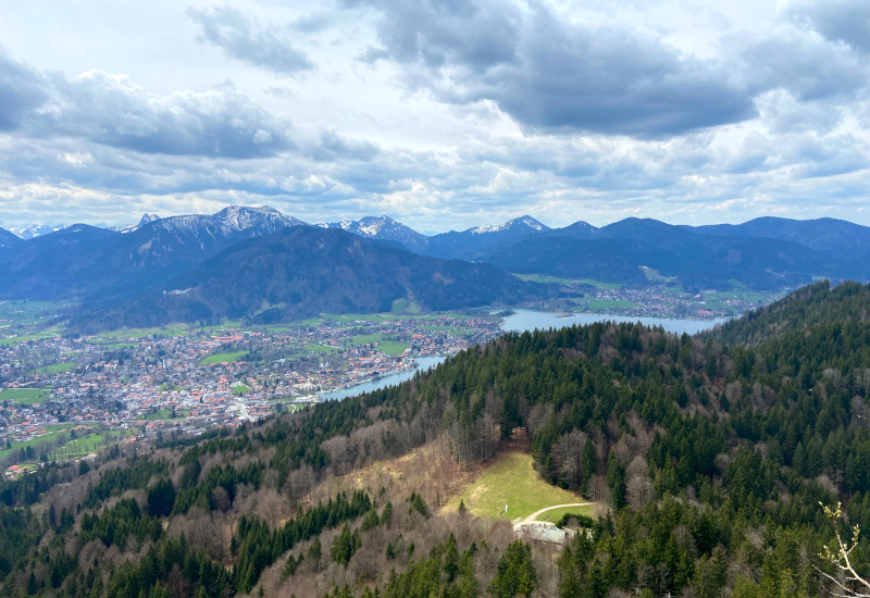 Berglandschaft mit Wald, See und schneebedeckten Bergen.