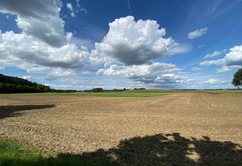 Weite Landschaft mit Wolken und bearbeitetem Feld.