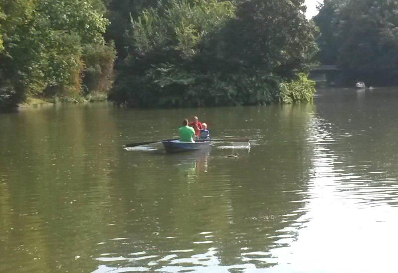 Familie rudert in einem Boot auf ruhigem Wasser.