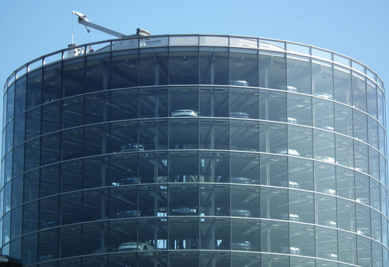 Gläserner Parkhaus mit mehreren Autos in Etagen.
