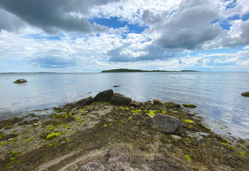 Ruhiger See mit Steinen und bewölktem Himmel.
