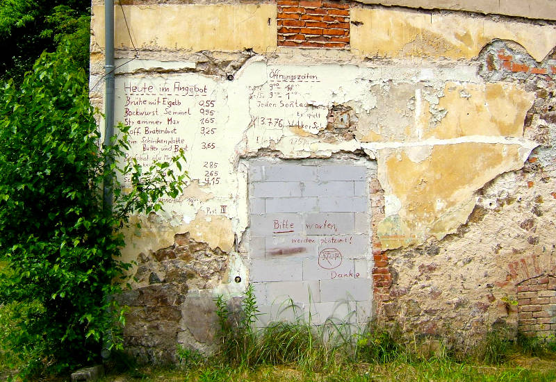 Wand mit Speiseangebot, Öffnungszeiten und Graffiti.