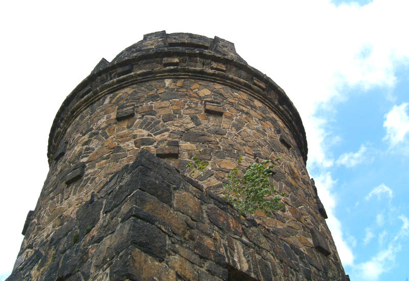 Steinerner Turm unter blauem Himmel mit Wolken.