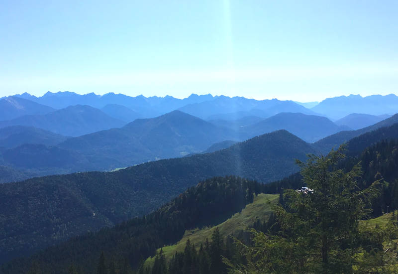 Berglandschaft mit vielen Hügeln und blauen Bergen im Hintergrund.