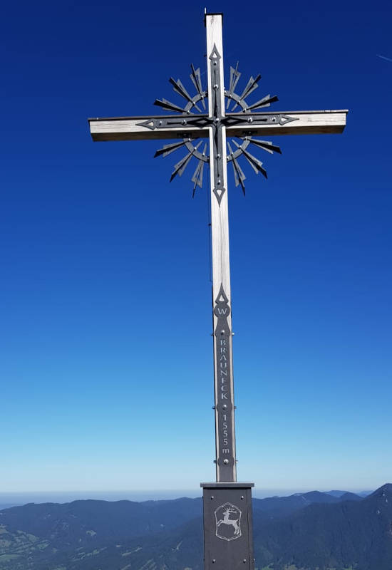 Kreuz auf einem Berggipfel mit klarem blauen Himmel.